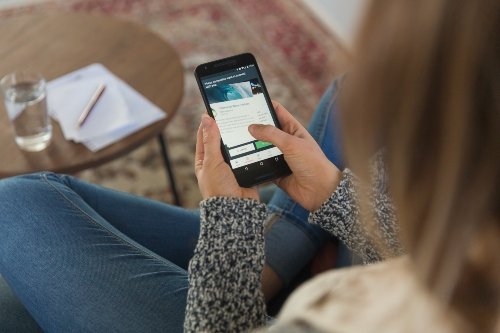 Was hilft bei Antriebslosigkeit? Keine Ablenkung zulassen! Frau im Schneidersitz mit Smartphone in der Hand.